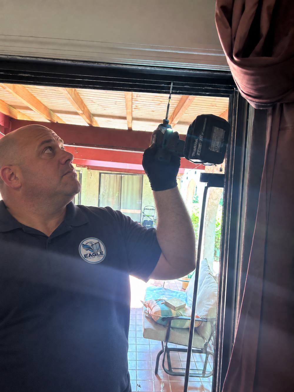 Eagle Sliding Doors technician working overhead on a sliding door track with a drill